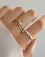 Model wearing gold stackable rings featuring a diamond cluster ring, a simple ring band, and a graduated promise ring