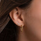 Model wearing dainty gold hoops with spiral design, and a solitaire stud earring