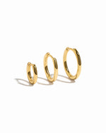 Three gold hoop earrings of different sizes on a white background