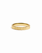 Gold textured ridged ring on white background. 