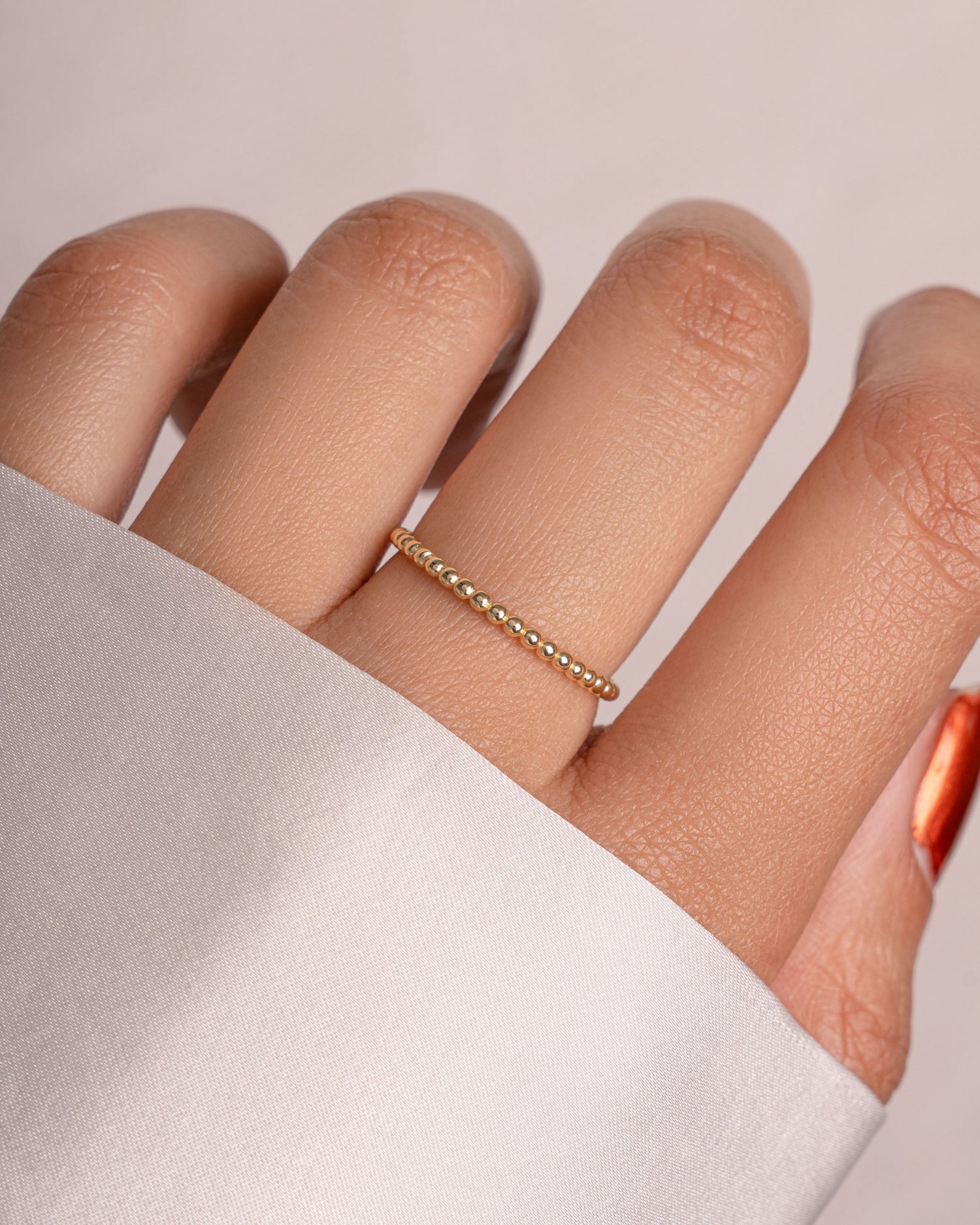 Gold plain beaded ring on a finger 