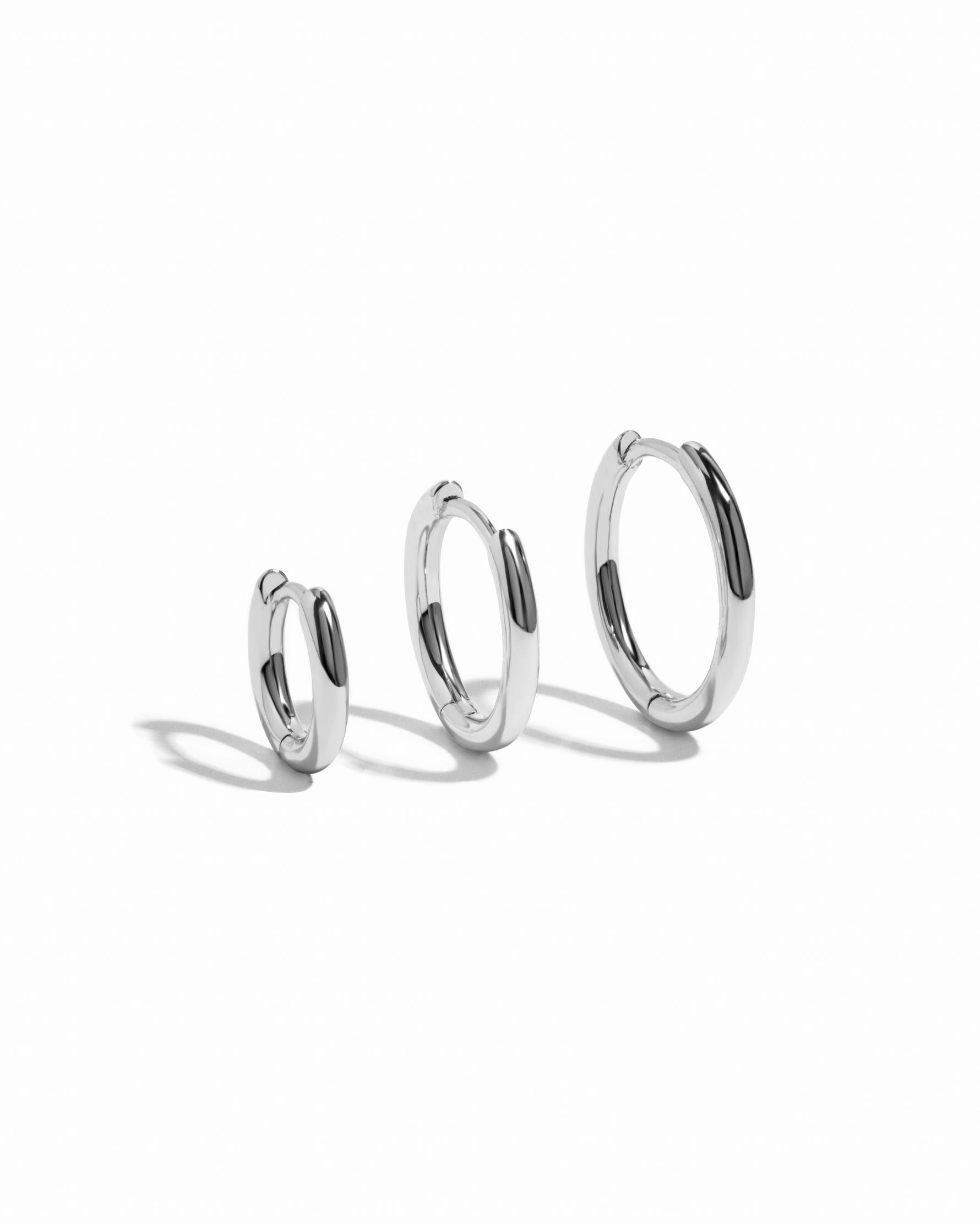 Three silver hoop earrings of different sizes on a white background