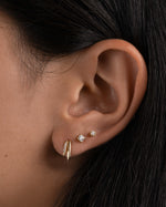 Gold unique earring with small stud earrings on model