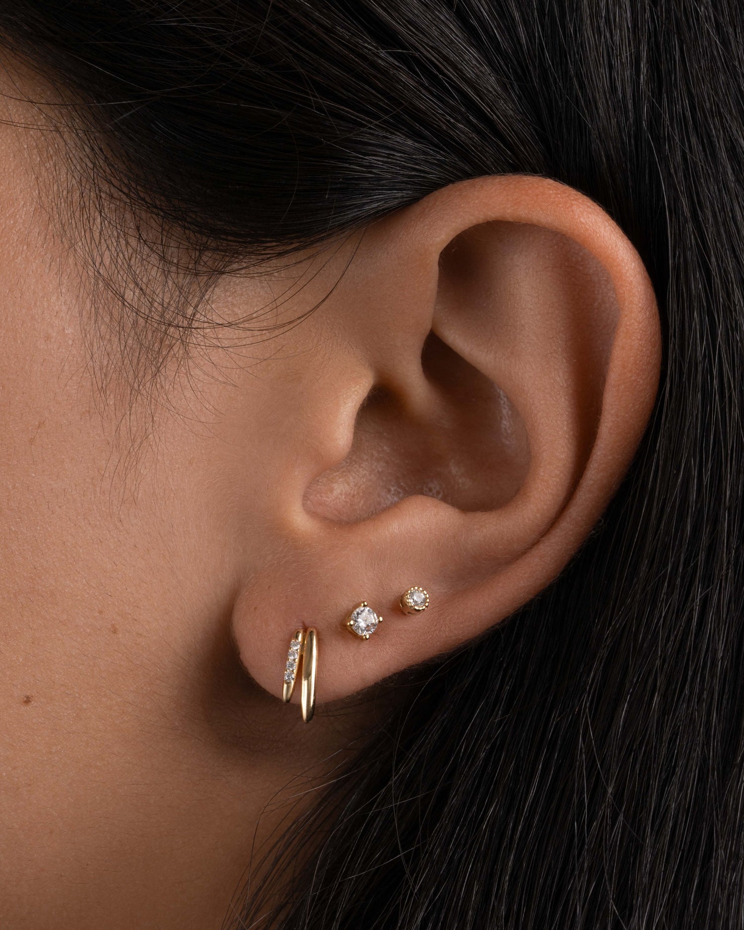 Gold unique earring with small stud earrings on model