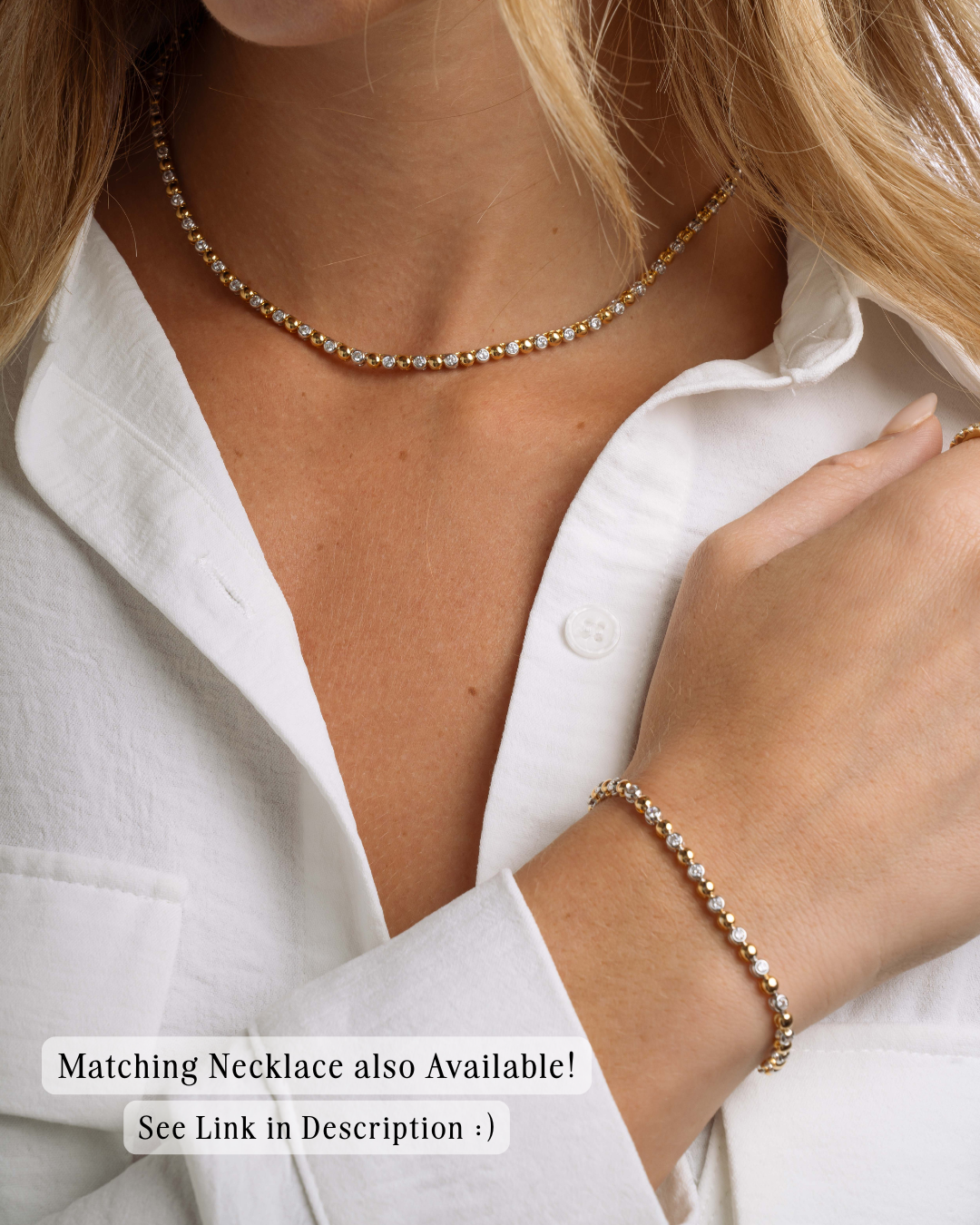 Person wearing a gold mixed metal tennis necklace and a matching mixed metal bracelet with a white shirt.