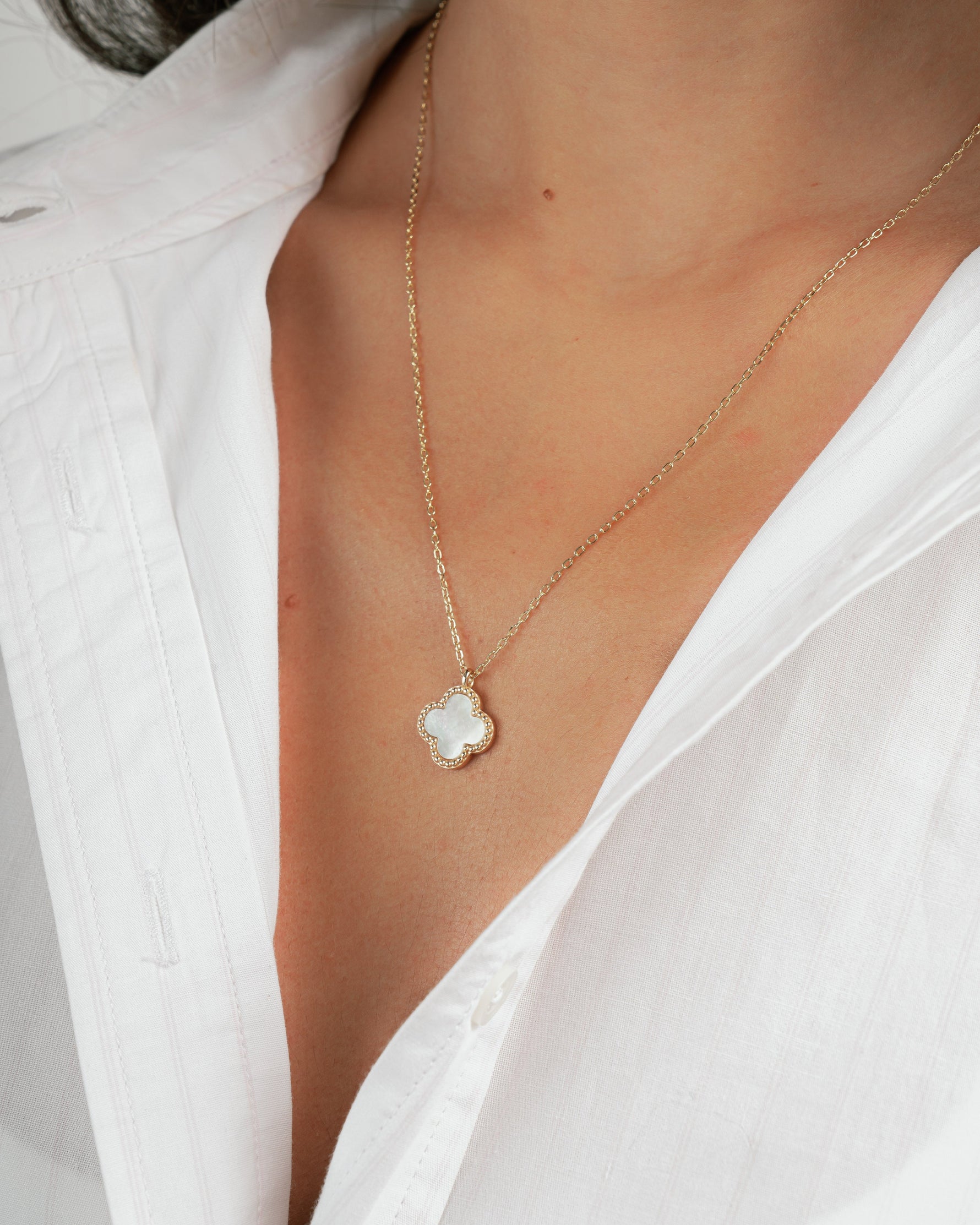 closeup image of model wearing dainty gold pendant necklace with pearl charm