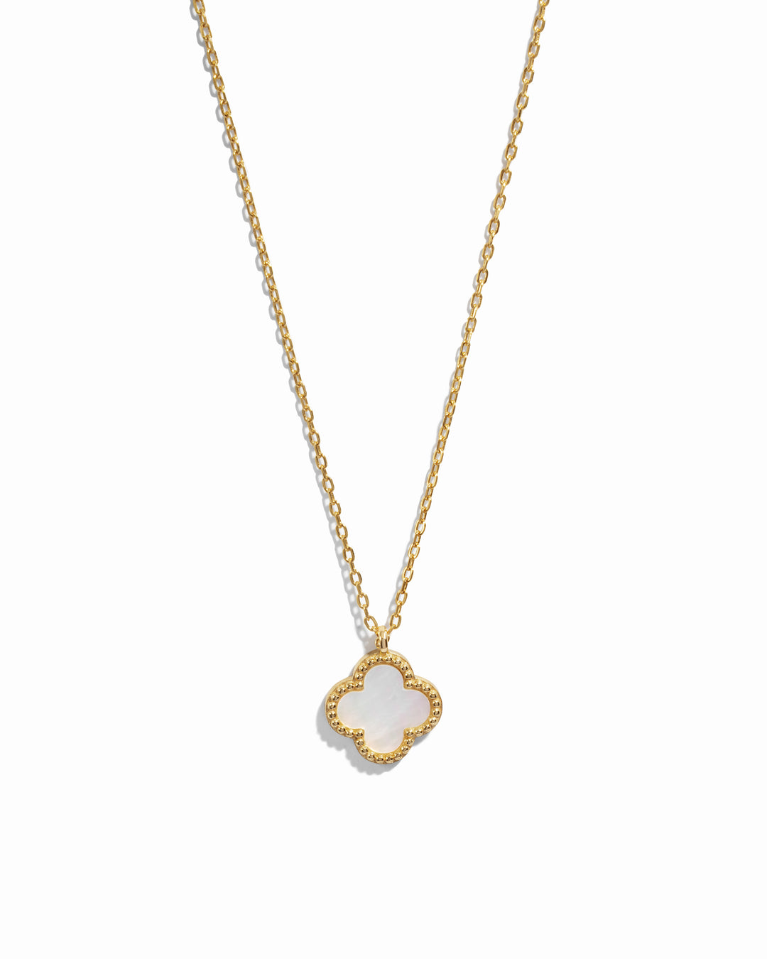 Gold necklace with a clover-shaped pendant set with mother of pearl on a white background