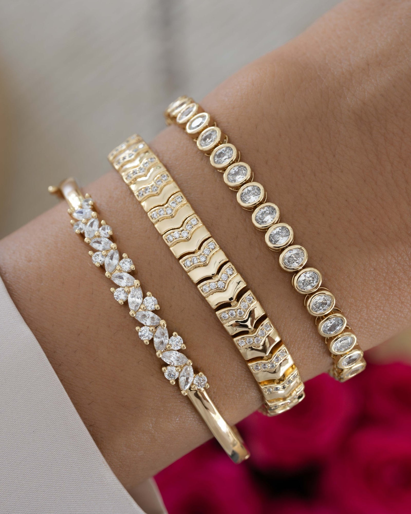 Model wearing gold bracelet stack featuring a oval bezel gold tennis bracelet,  a gold chain bracelet and a diamond bangle bracelet