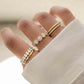 model wearing gold ring stack featuring diamond multi stone ring, oval diamond eternity band, 5 stone halo ring, spiral band ring, cz eternity ring