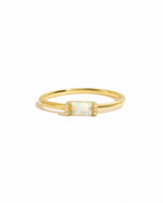 Gold ring with a central opal gemstone and pave cz stones on each side on a white background