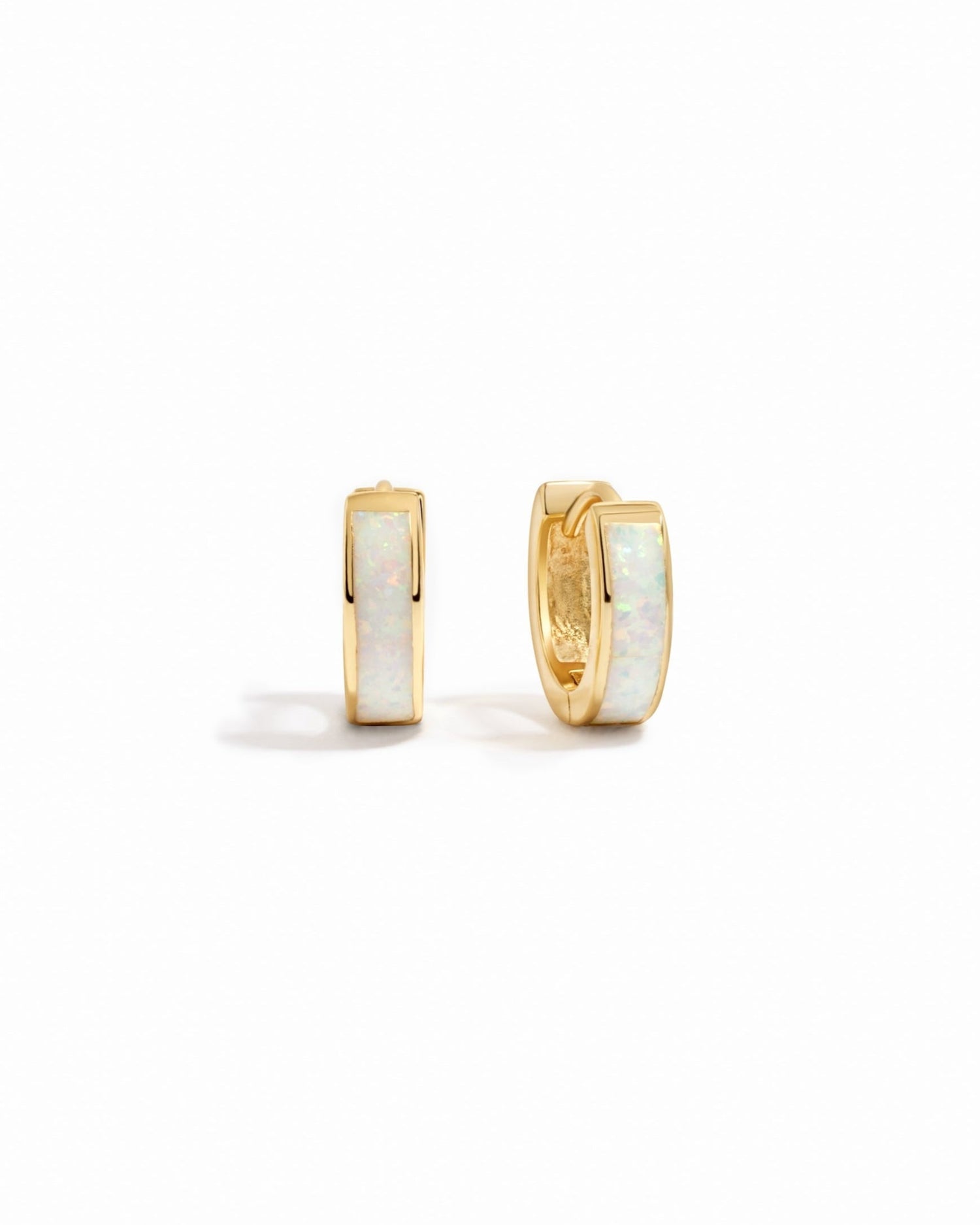 Gold hoop earrings with white opal stones on a white background