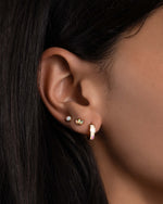 Model wearing dainty petal opal studs and opal huggies.