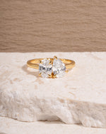 Gold diamond engagement ring with a toi et moi ring design on a textured surface