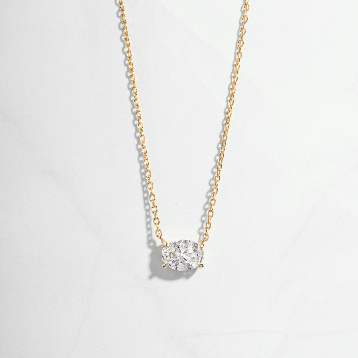 Closeup of solitaire oval diamond necklace in gold