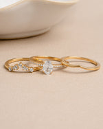 Gold wedding jewelry featuring a promise ring set on a beige background