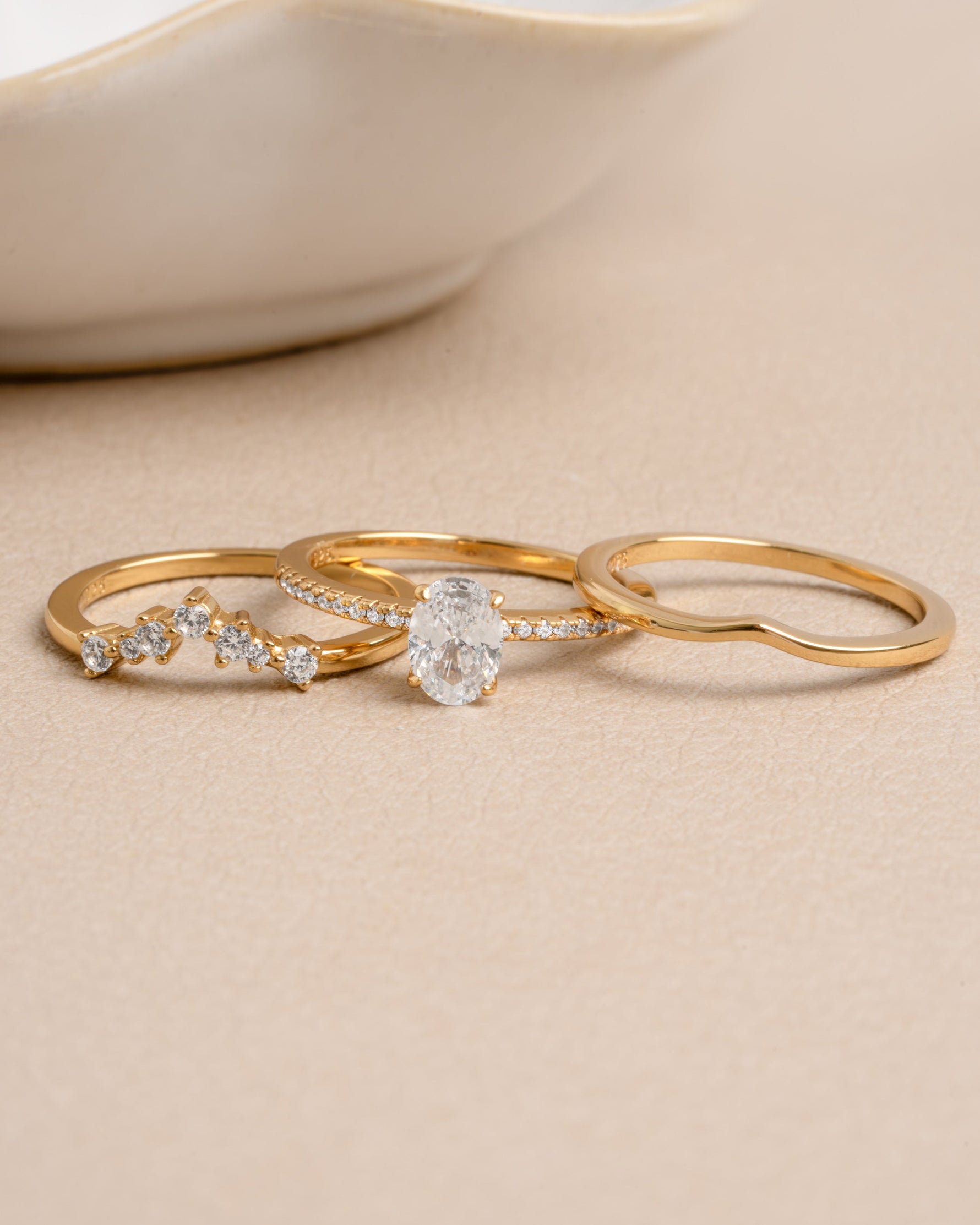 Gold wedding jewelry featuring a promise ring set on a beige background