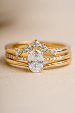 Gold oval diamond ring set on a beige background