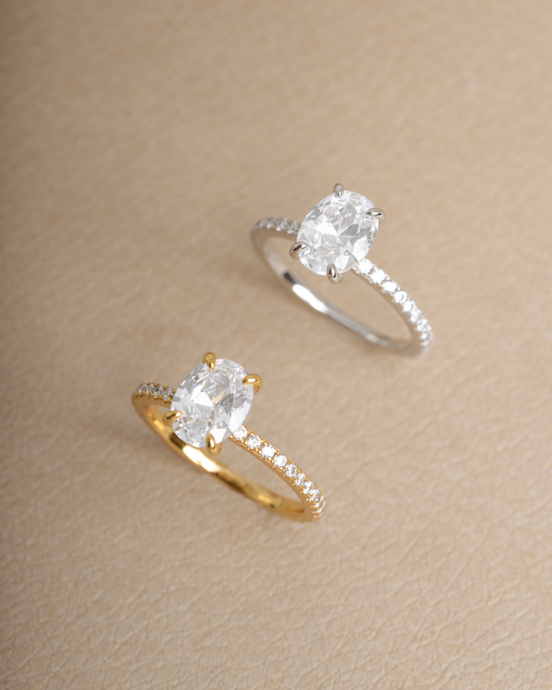 Two diamond rings, one gold promise ring and one sterling silver dainty engagement ring on a beige background
