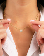 model holding gold pendant necklace with paperclip chain and halo baguette 