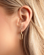 Model wearing gold paperclip hoop earrings