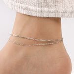 Model showcasing a set of silver chain anklets.