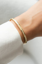 Gold diamond bangle bracelet on a wrist with a white background
