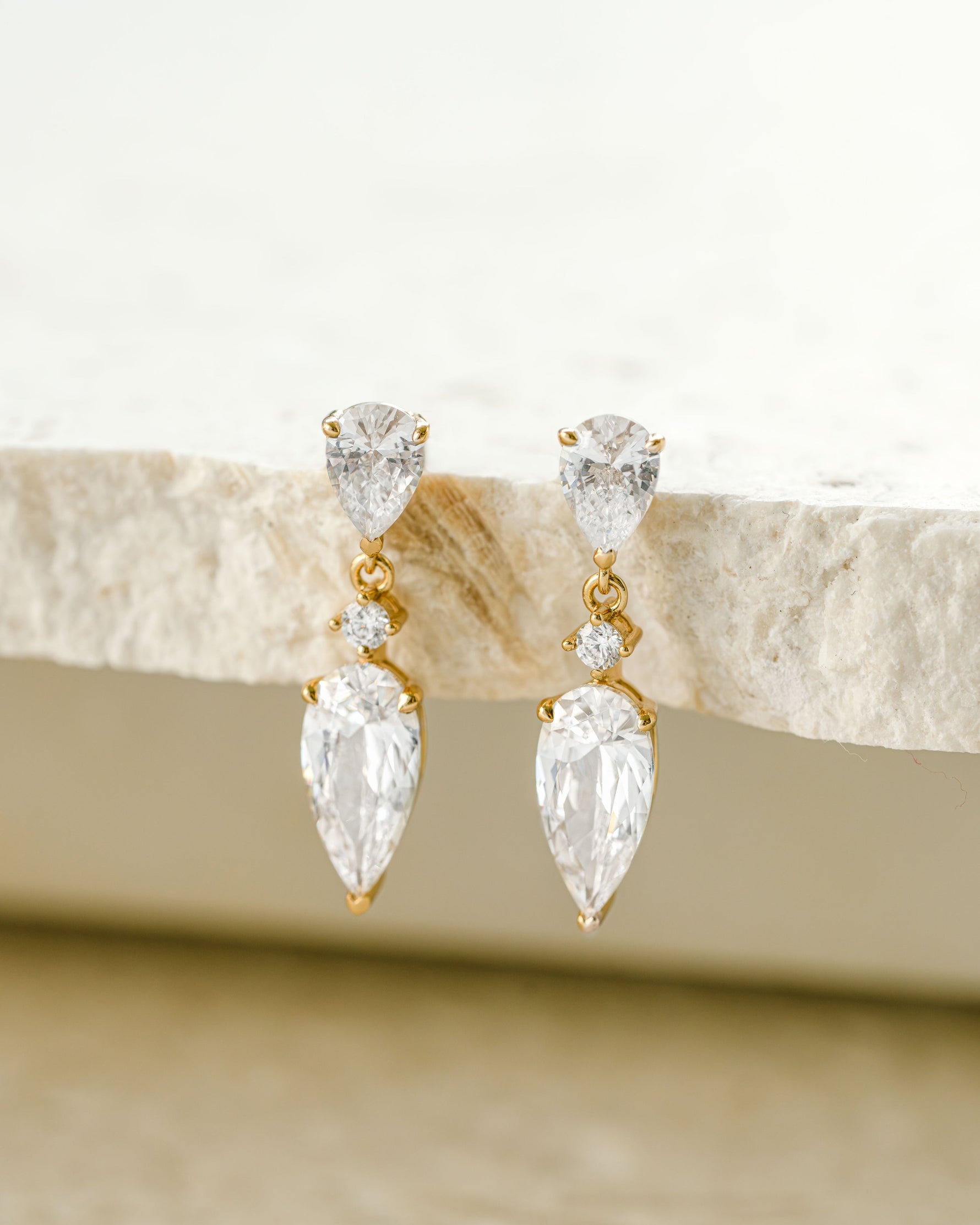 Gold dainty stud earrings with a diamond pear cut drop earring design