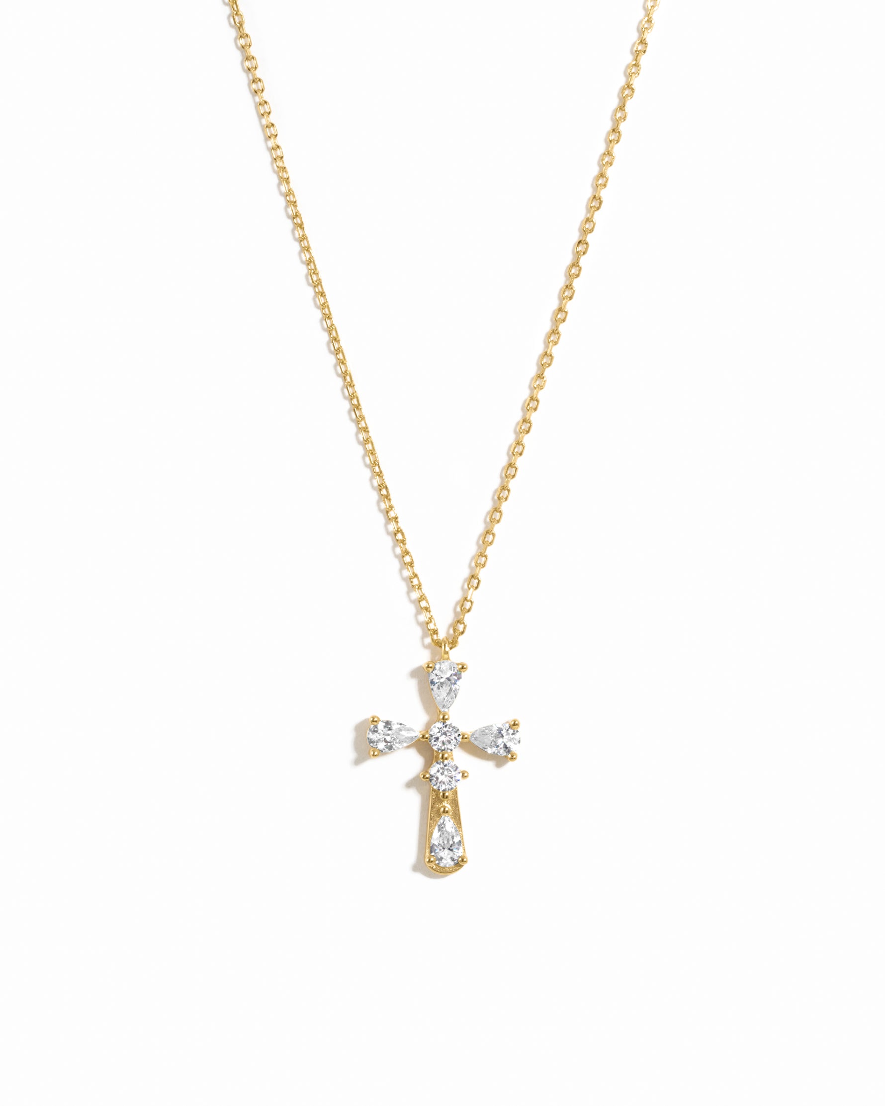 Gold cross necklace with pear cut diamonds on a white background