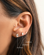 Close-up of an ear wearing wedding jewelry featuring gold diamond studs with multiple size variations, a 5x7mm diamond earrings, a 4x6mm dainty earring, and a 2x3mm tiny earring.