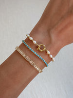 model wearing pearl bracelet, turquoise bracelet, and baguette tennis bracelet