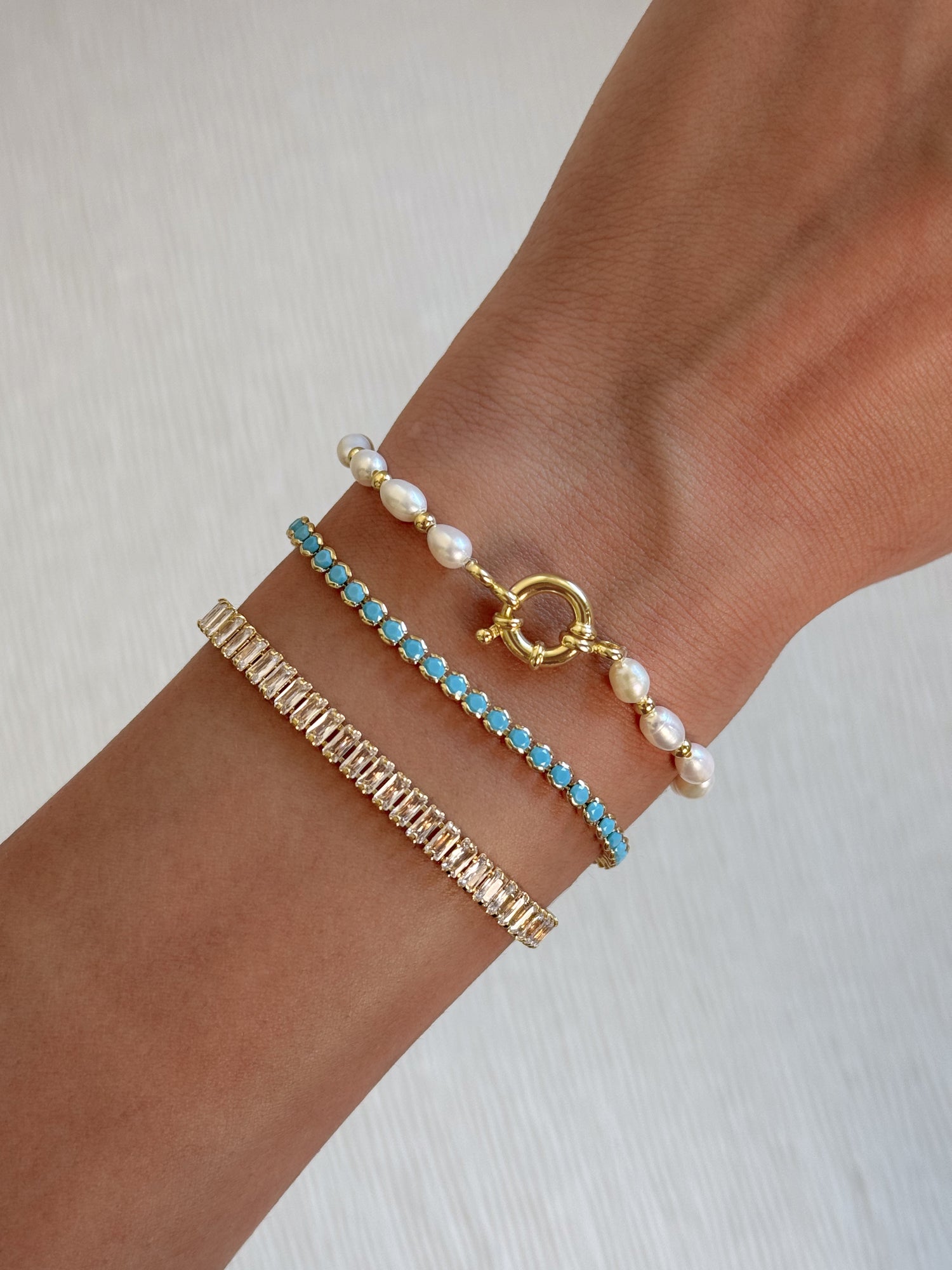 model wearing pearl bracelet, turquoise bracelet, and baguette tennis bracelet