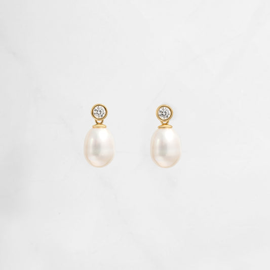 closeup image of gold drop earrings with a freshwater pearl and cubic zirconia bezel-set stone