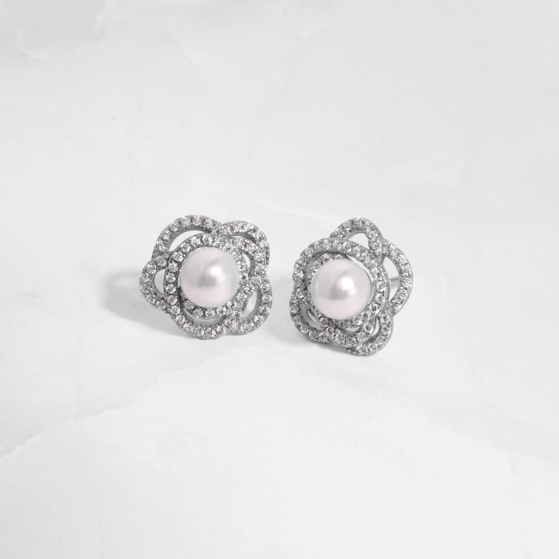 closeup image of sterling silver statement earrings with pearl earring design and floral earring design
