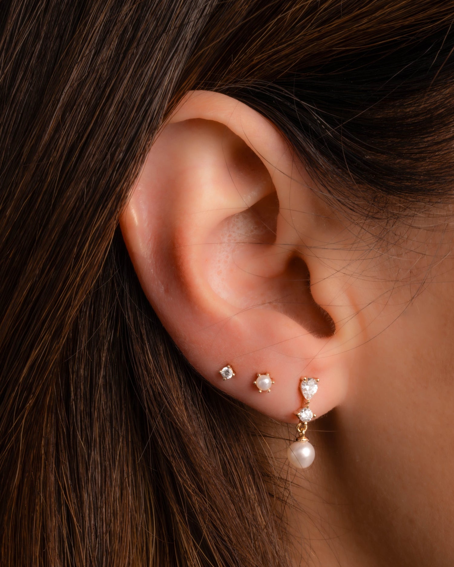 model wearing gold pearl earrings featuring pearl drop earrings, pearl studs, and cz studs