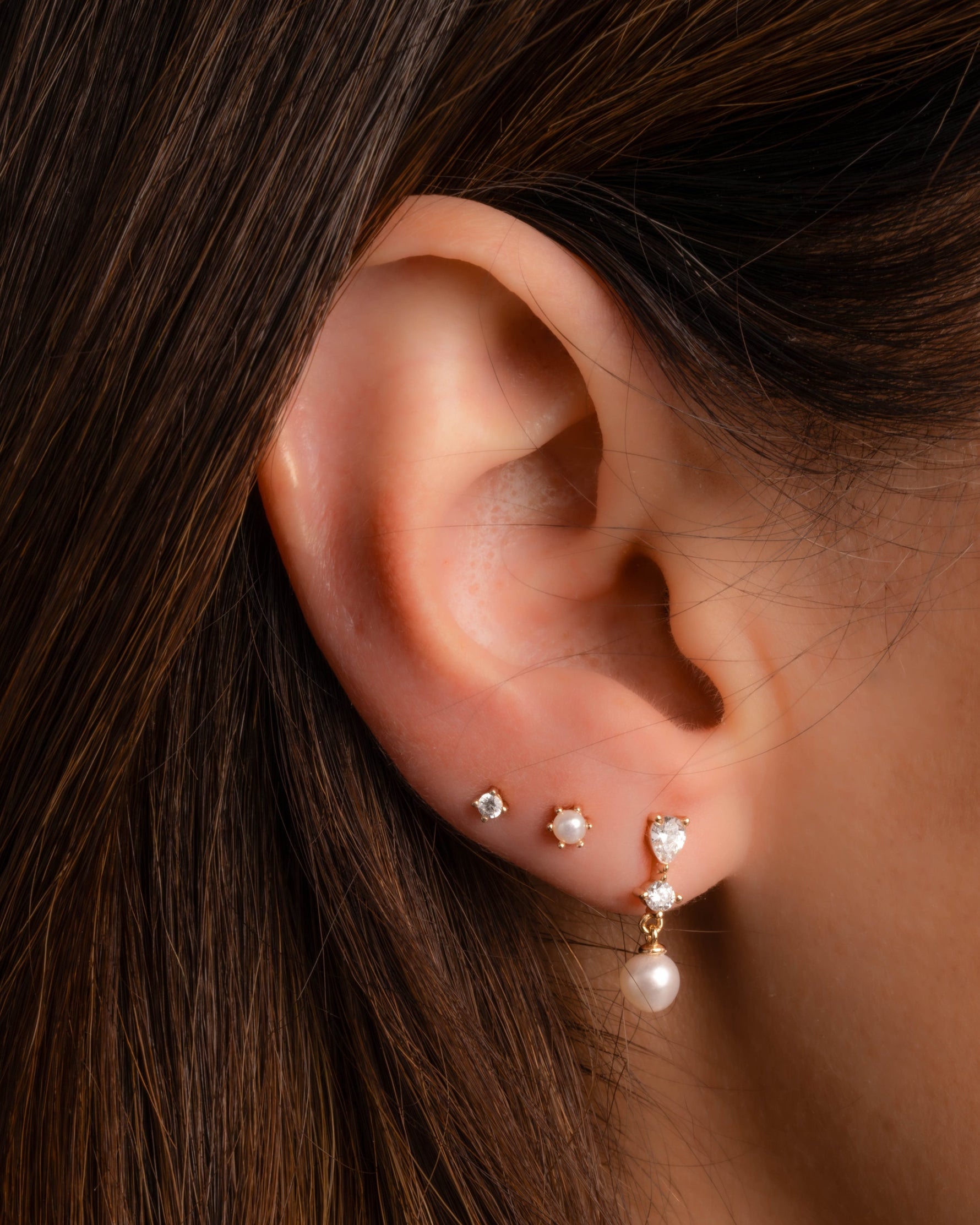 model wearing gold pearl earrings featuring pearl drop earrings, pearl studs, and cz studs
