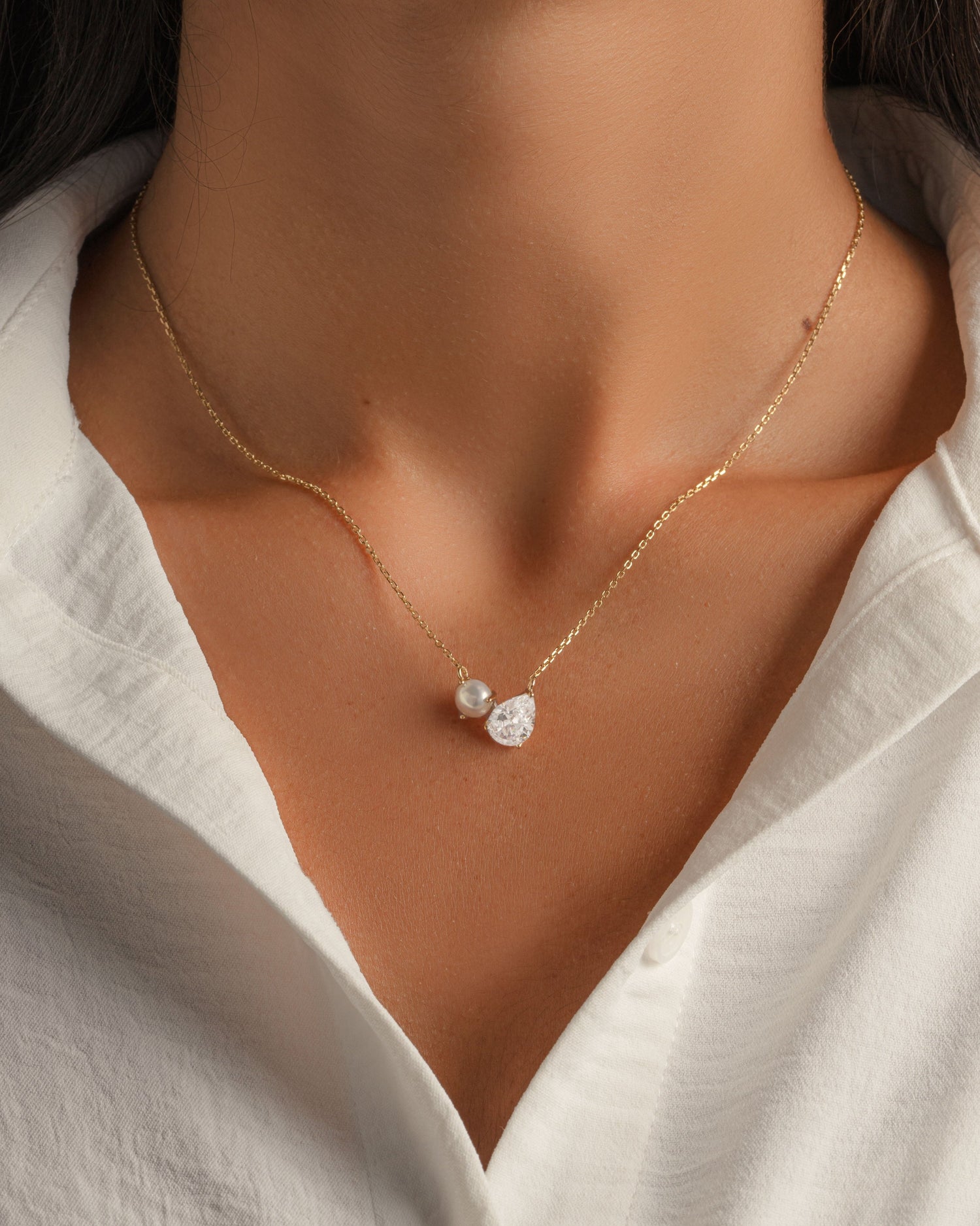 Gold pearl necklace on a gold chain with a pear cut diamond