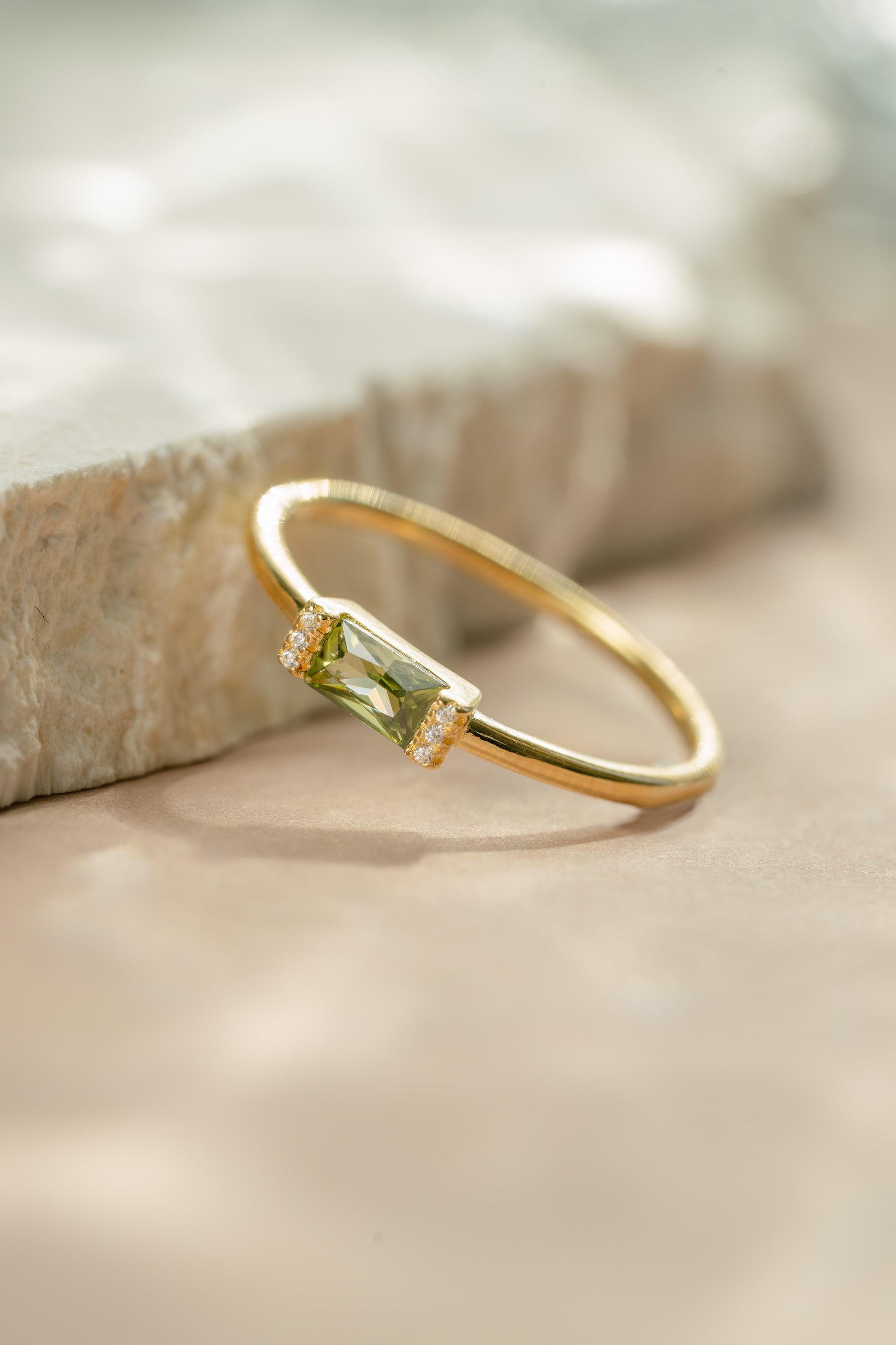 Gold peridot baguette cut gemstone ring laying on a slant