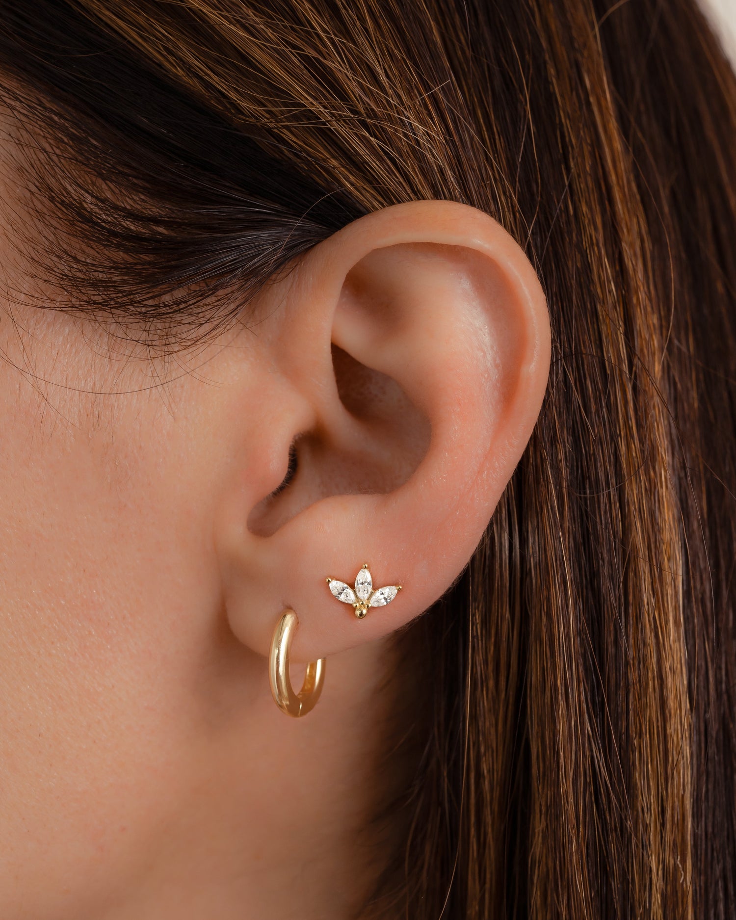 closeup image of model wearing gold petal stud earrings and minimalist hoop earrings