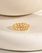 Gold chain ring on a beige ceramic surface