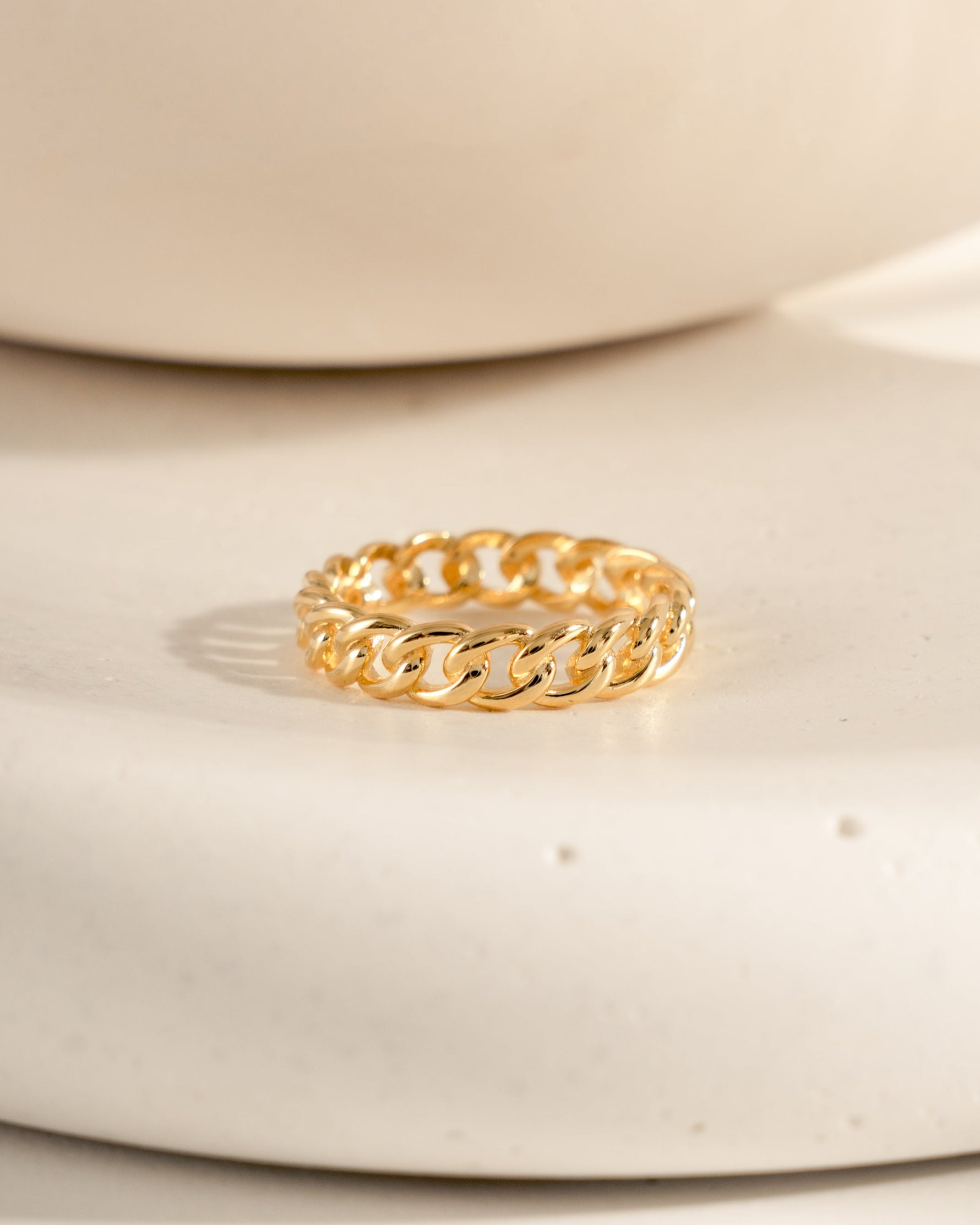Gold chain ring on a beige ceramic surface