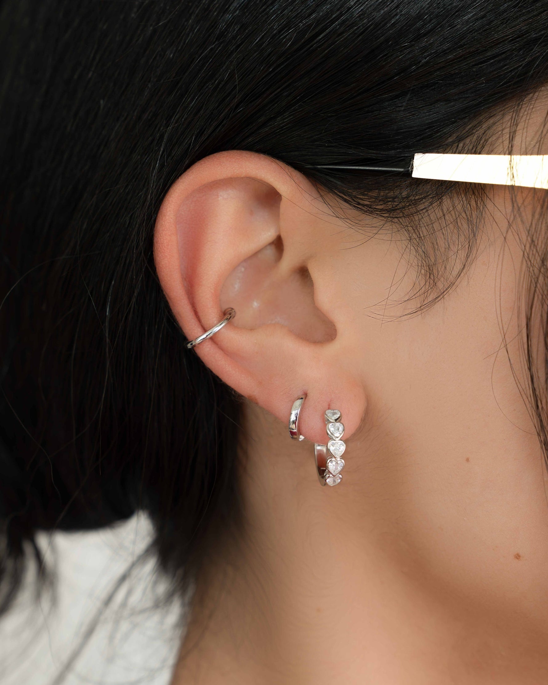 Model wearing sterling silver hoop earrings and a dainty silver ear cuff.