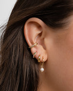 Model wearing dainty gold earrings in ear.