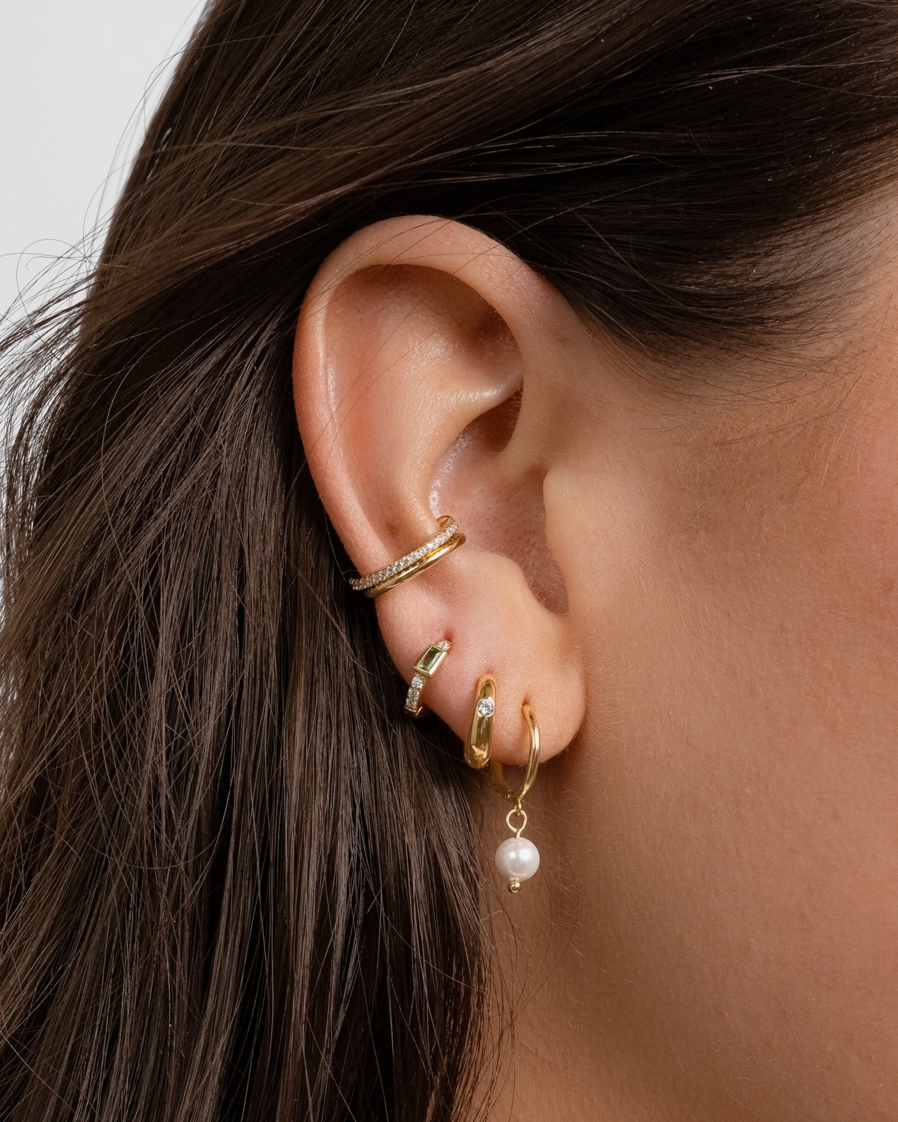 Model wearing dainty gold earrings in ear.