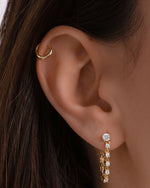 Close-up of an ear wearing gold hoop cartilage earring and a cz drop earring 