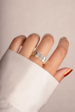 Model wearing stacked gold and silver ridged textured rings. 