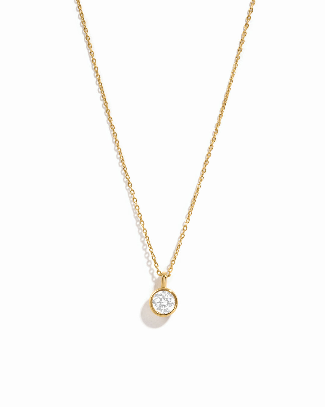 Gold necklace with a small diamond pendant on a white background