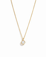 Gold necklace with a small diamond pendant on a white background
