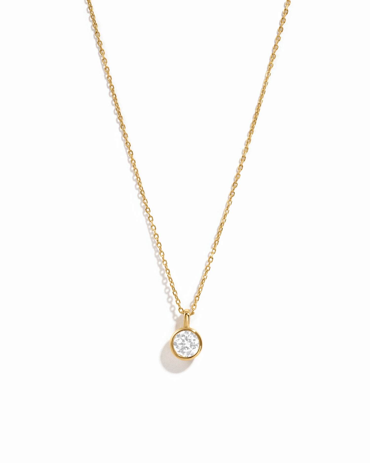Gold necklace with a small diamond pendant on a white background
