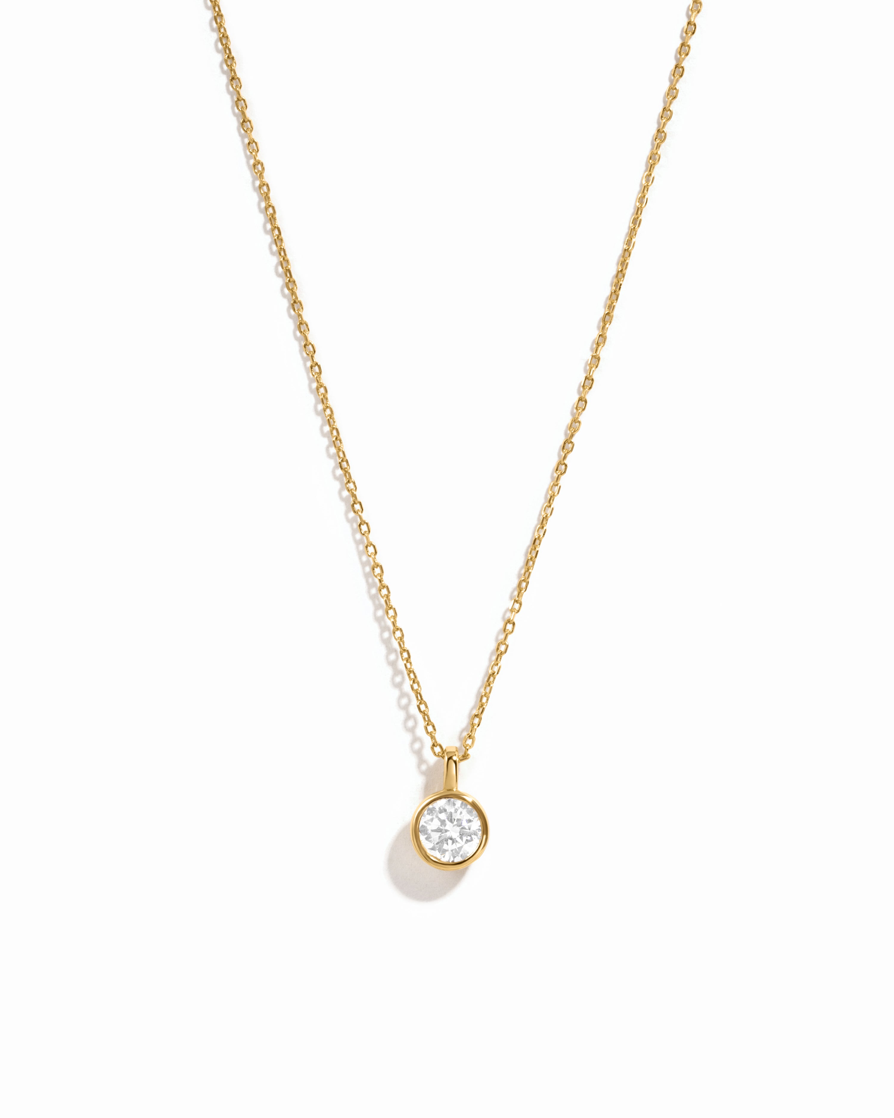 Gold necklace with a small diamond pendant on a white background