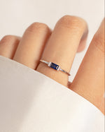 Silver ring with a sapphire stone on models hands